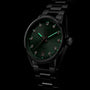 The TAG Heuer Carrera Date is a black metal wristwatch with a green sunray-brushed dial, diamond hour markers, date display at 6 o’clock, and Carrera branding.