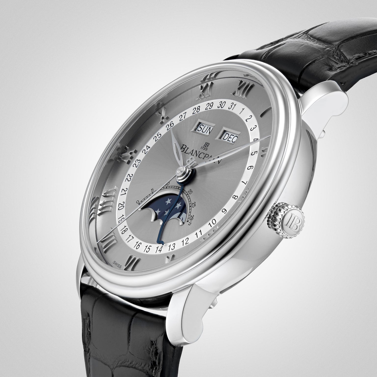 The Blancpain Villeret Quantième Complet is a luxury silver wristwatch featuring Roman numerals, a moonphase display, and a black leather strap, shown against a light background.