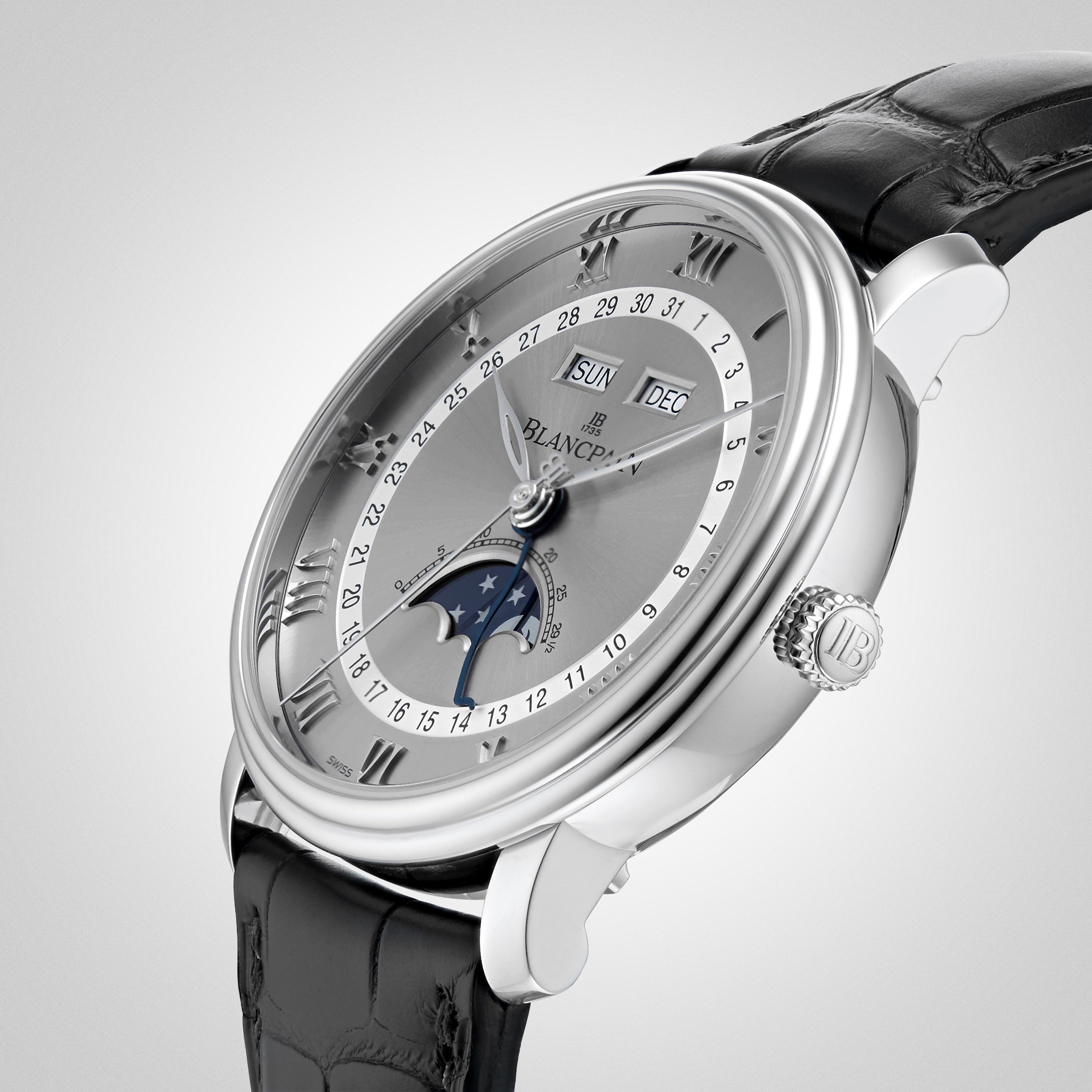 The Blancpain Villeret Quantième Complet is a luxury silver wristwatch featuring Roman numerals, a moonphase display, and a black leather strap, shown against a light background.