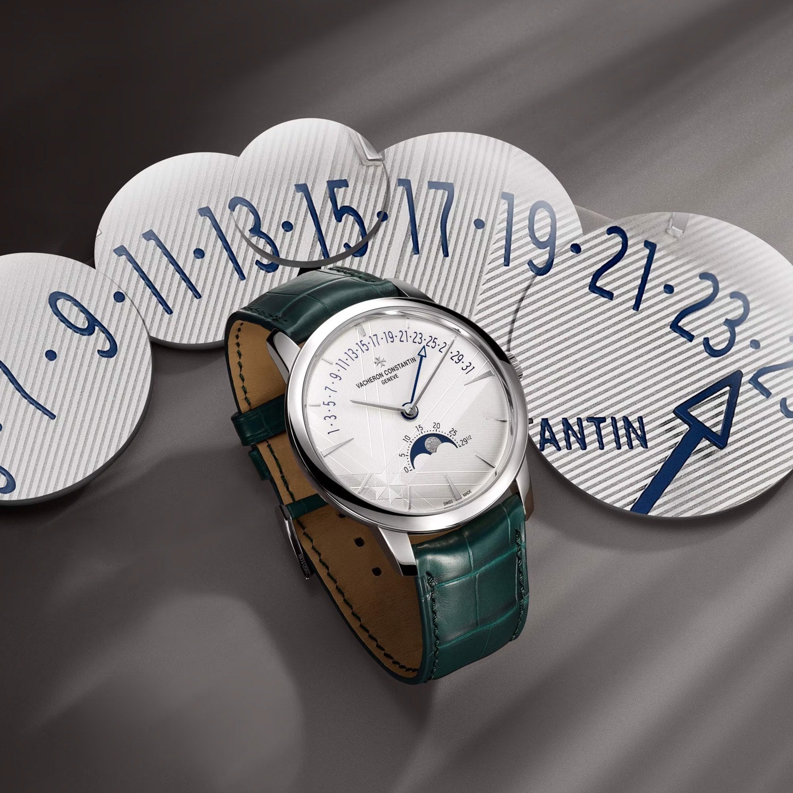 The Vacheron Constantin Patrimony Moon Phase Retrograde Date, a luxury wristwatch with a green leather strap, is showcased on blue-numbered discs, featuring a precise moon phase and calendar—an exquisite limited edition timepiece.