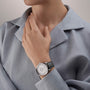 A person in a light blue collared shirt showcases a Vacheron Constantin Traditionnelle Manual-Winding platinum watch with a black leather strap on their left wrist.