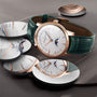 The Vacheron Constantin Patrimony Moon Phase Retrograde Date is a limited edition luxury wristwatch with a green leather band, 18K pink gold case, and moon phase dial, elegantly showcased on a gray surface.