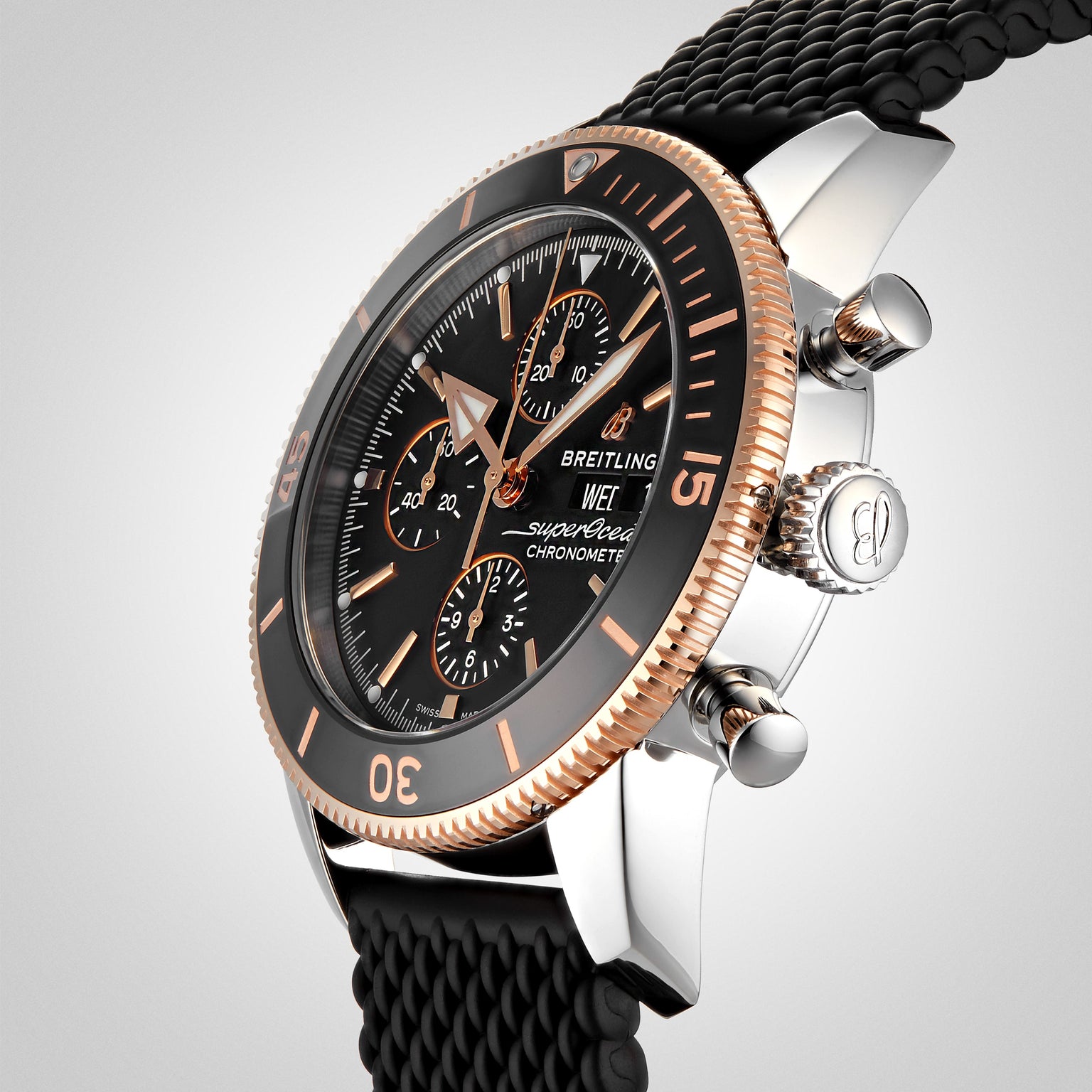 A close-up of the Breitling Superocean Heritage B20 Automatic 44 with a black dial, ceramic bezel, rose gold accents, and a black textured strap.