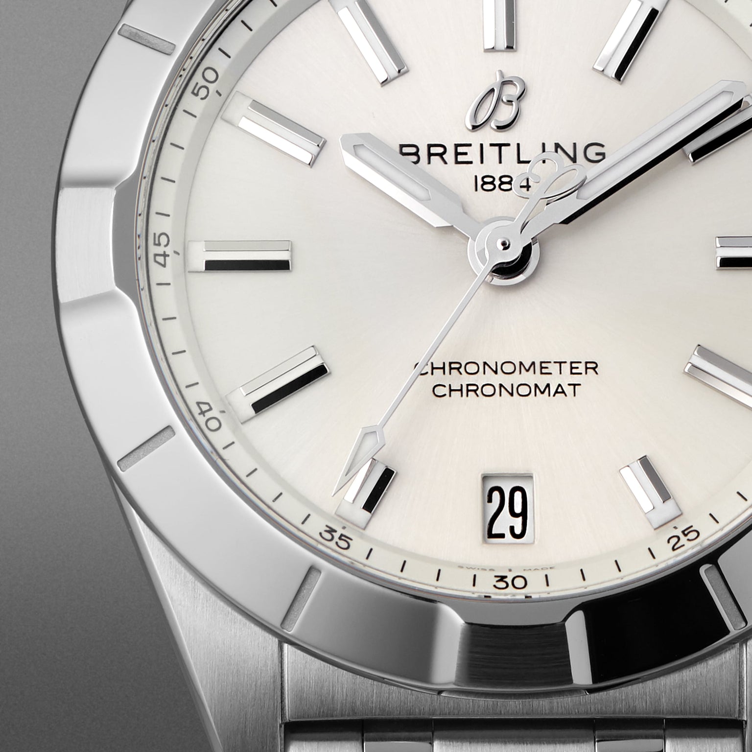 Close-up of a Breitling Chronomat 32 watch featuring a white dial, silver hour markers, date window at 6 o’clock, and stainless steel case and bracelet; COSC-certified chronometer.