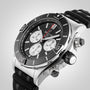 A close-up of a stainless steel Breitling Super Chronomat B01 44 chronograph with a black bezel, three subdials, and a black textured strap, powered by the COSC-certified Breitling 01 calibre.