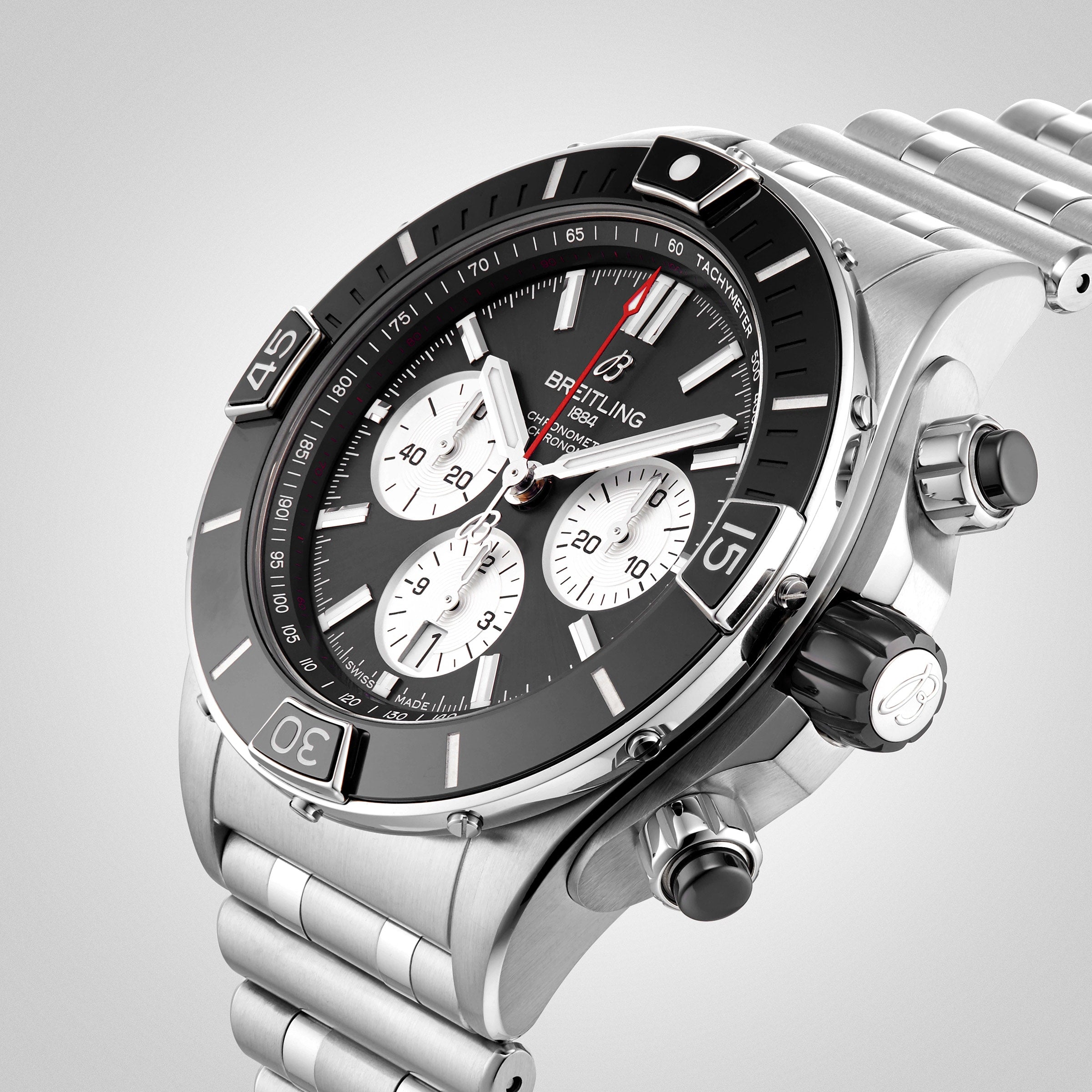 A close-up of the Breitling Super Chronomat B01 44 shows its black bezel, Rouleaux bracelet, and three white sub-dials on a black face, powered by the precise Breitling 01 movement.