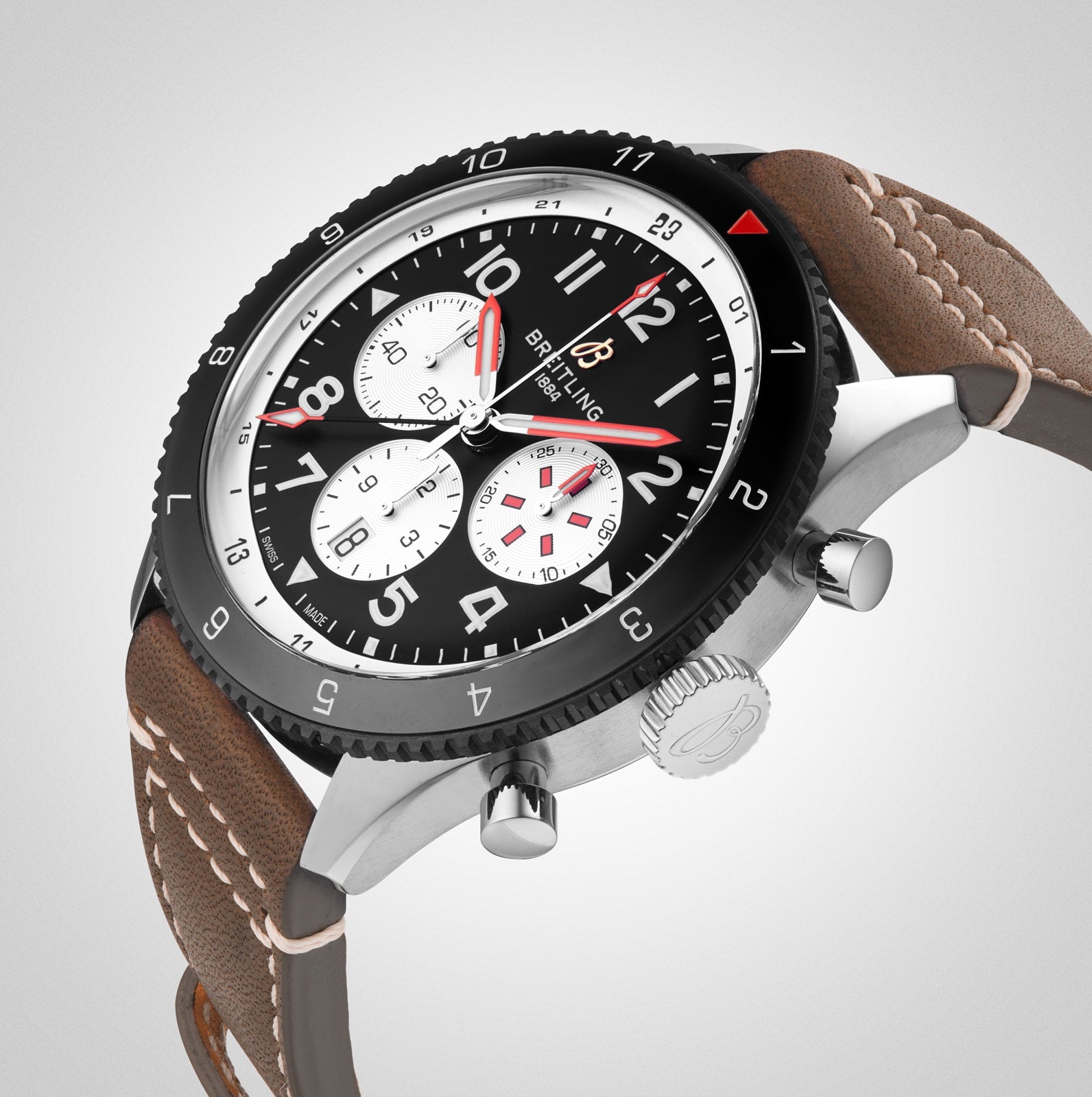 The Breitling Super AVI B04 Chronograph GMT 46 Mosquito features a black dial with three white subdials, red and white hands, a stitched brown leather strap, and a stainless steel case inspired by aviation history.