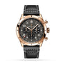 The Breitling Super AVI B04 Chronograph GMT 46 P-51 Mustang features a black dial, gold case, three subdials, date window, and a black leather strap with white stitching, shown on a white background.