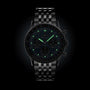 A Breitling Navitimer B01 Chronograph 41 wristwatch features a black dial, metal link band, and luminous green markers and hands, displayed against a dark background.