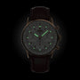 The Breitling Navitimer B01 Chronograph 41, featuring a dark leather strap and luminous green hour markers and hands, is displayed against a black background—an iconic pilot’s watch celebrated for precision and timeless style.