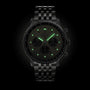 A Breitling Navitimer B01 Chronograph 43 pilot’s watch in black with a metal bracelet and glowing green markers and hands is displayed against a black background.