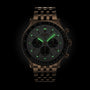 The Breitling Navitimer B01 Chronograph 46 is a metallic pilots watch with a round face and linked metal band, featuring faint green luminescent markers and hands for aviation-inspired style in the dark.