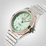 The Breitling Super Chronomat Automatic 38 wristwatch features a green dial, chronometer-certified movement, diamond-set bezel, gold accents, and a silver and gold bracelet, displayed on a light background.