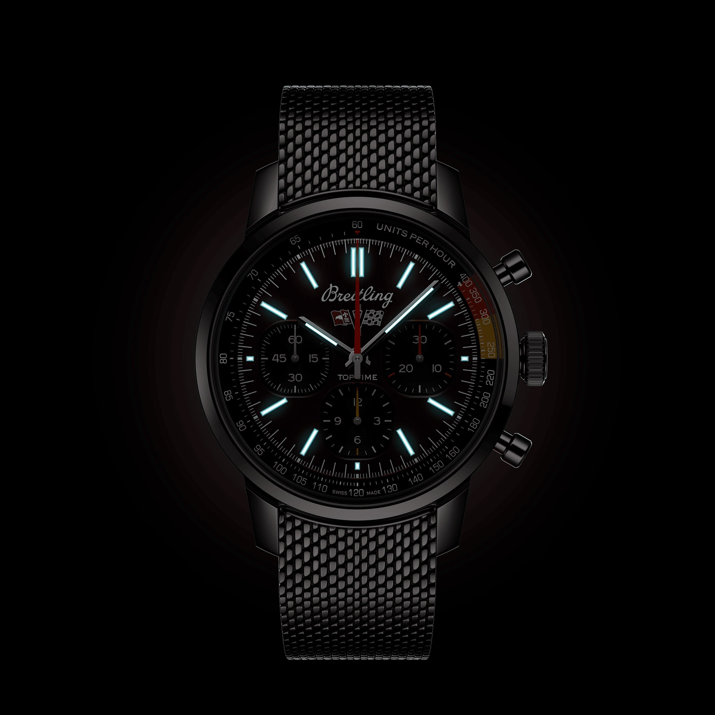 The Breitling Top Time B01 Chevrolet Corvette is a black racing chronograph with a mesh strap, luminous hour markers, multiple subdials, and a tachymeter bezel, powered by the Manufacture Calibre 01 and shown against a dark background.