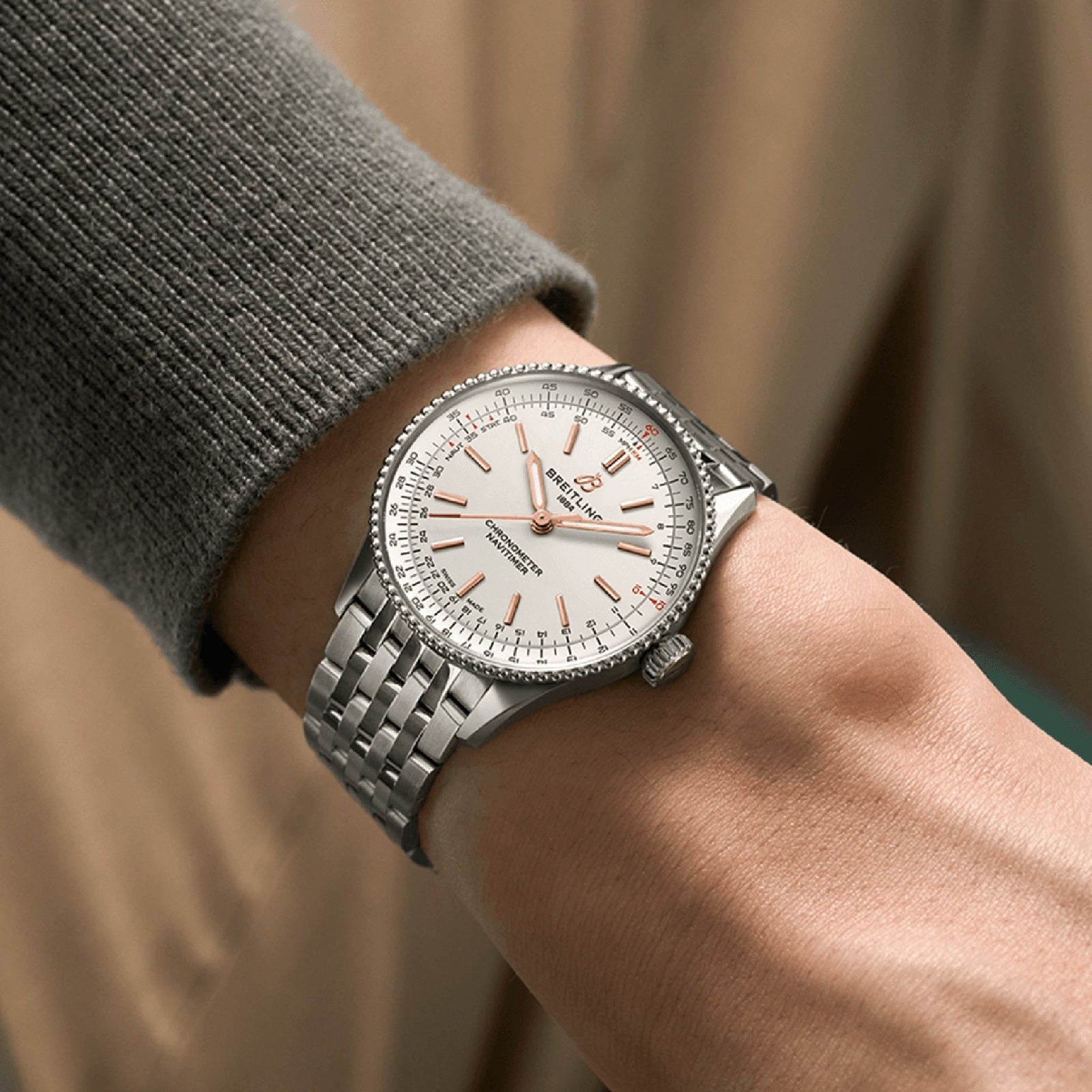 A close-up of a person wearing a Breitling Navitimer Automatic 36 with a silver case, white dial, and metal link band on their left wrist.