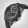 A close-up of the Breitling Avenger B01 Chronograph 44 Night Mission, a black wristwatch with a textured strap, black dial, multiple subdials, and a rotating bezel.