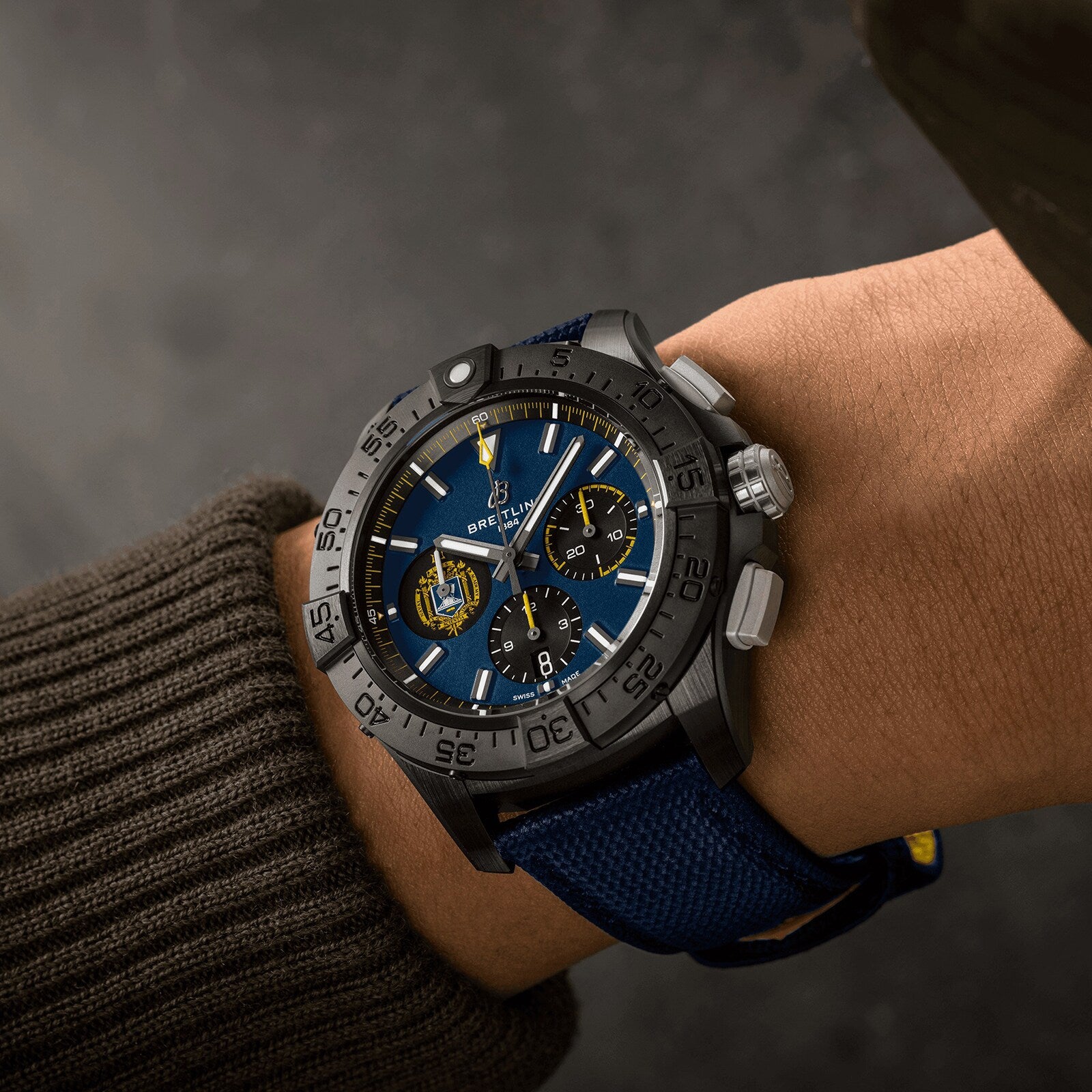 A person wearing a Breitling Avenger B01 Chronograph 44 Night Mission US Naval Academy with a blue dial, black bezel, and blue strap featuring the renowned Manufacture Caliber 01, seen from above.