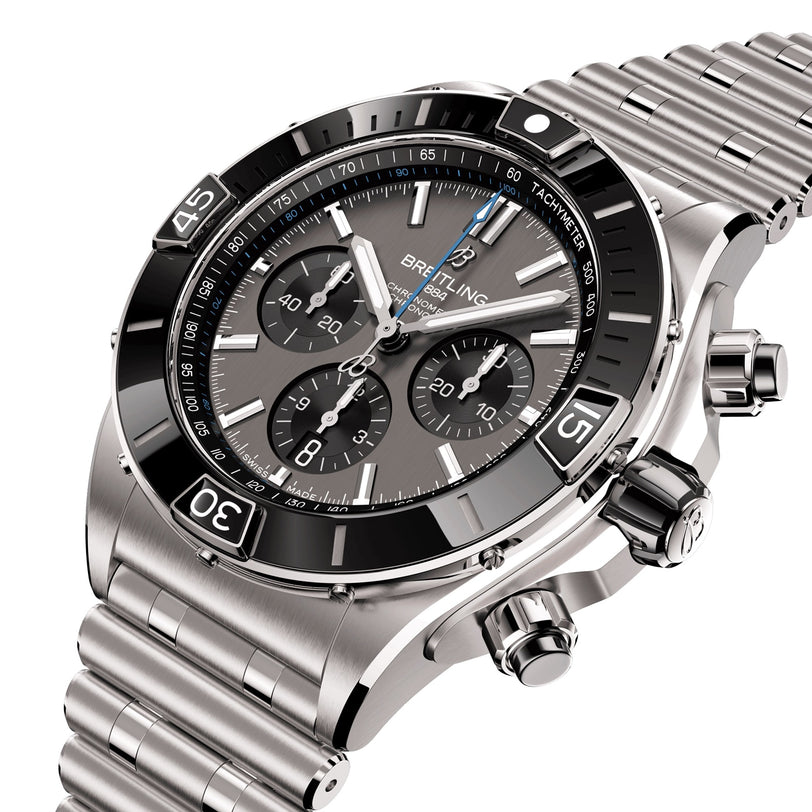 The Breitling Super Chronomat B01 44, a stainless steel chronograph with black tachymeter bezel, three subdials, and link bracelet, is shown at an angle and powered by the precise Breitling 01 calibre.
