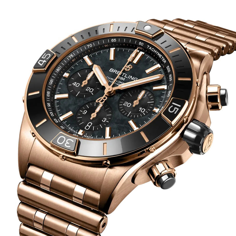 A close-up of the Breitling Super Chronomat B01 44, featuring a rose gold case, black bezel and dial, three subdials, and a metal link bracelet.