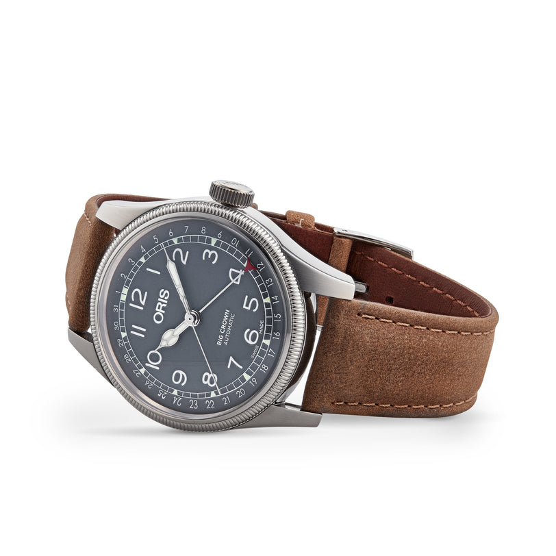 The Oris Big Crown Pointer Date wristwatch features a silver case, gray dial with white numerals, brown leather strap, and sapphire glass, shown against a white background.