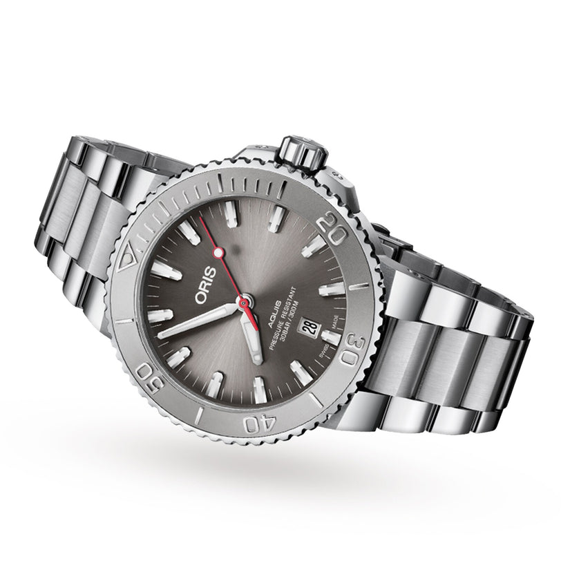 The Oris Aquis Date Relief is a silver wristwatch with a metal band, grey dial, and date display at 6 o’clock.