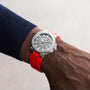 Someone wearing an Oris Aquis Date Relief watch featuring a grey dial and a red silicone strap on their wrist.