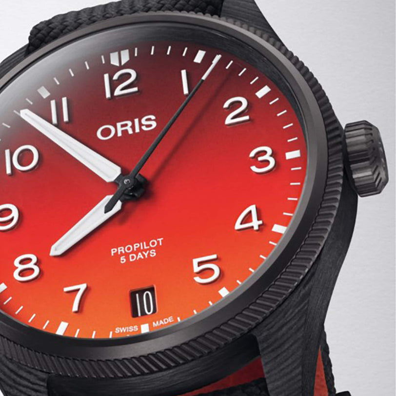 Close-up of the Oris ProPilot Coulson Limited Edition watch with a red gradient dial, white numerals, and a 3D printed carbon fibre case, inspired by Coulson Aviation. The time shown is about 10:08.