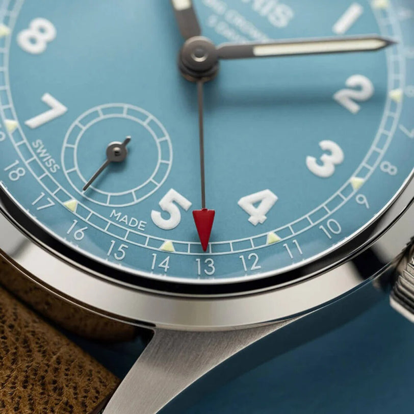 Close-up of the Oris Big Crown Pointer Date Calibre 473, featuring a blue dial with white numerals, red-tipped pointer at 13, brown leather strap, and powered by the hand-wound calibre 473.