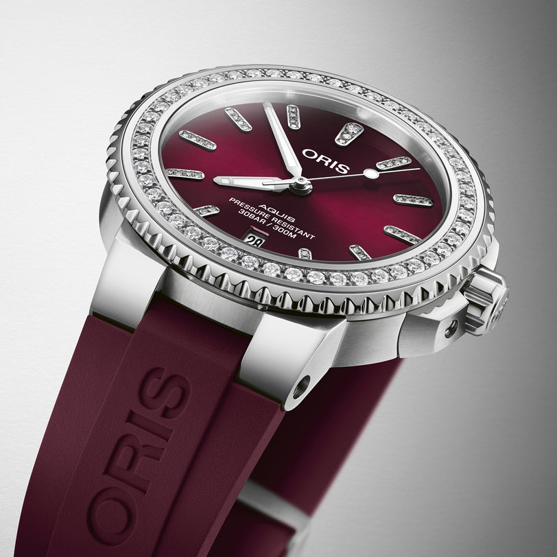 Close-up of the Oris Aquis Date Diamonds watch featuring a burgundy dial, diamond bezel, and a matching burgundy rubber strap.