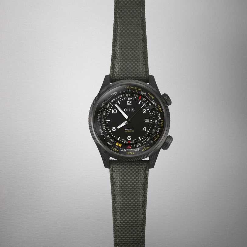 The Oris ProPilot Altimeter wristwatch, featuring a multi-colored dial and an olive-green woven strap, is shown against a plain light background.