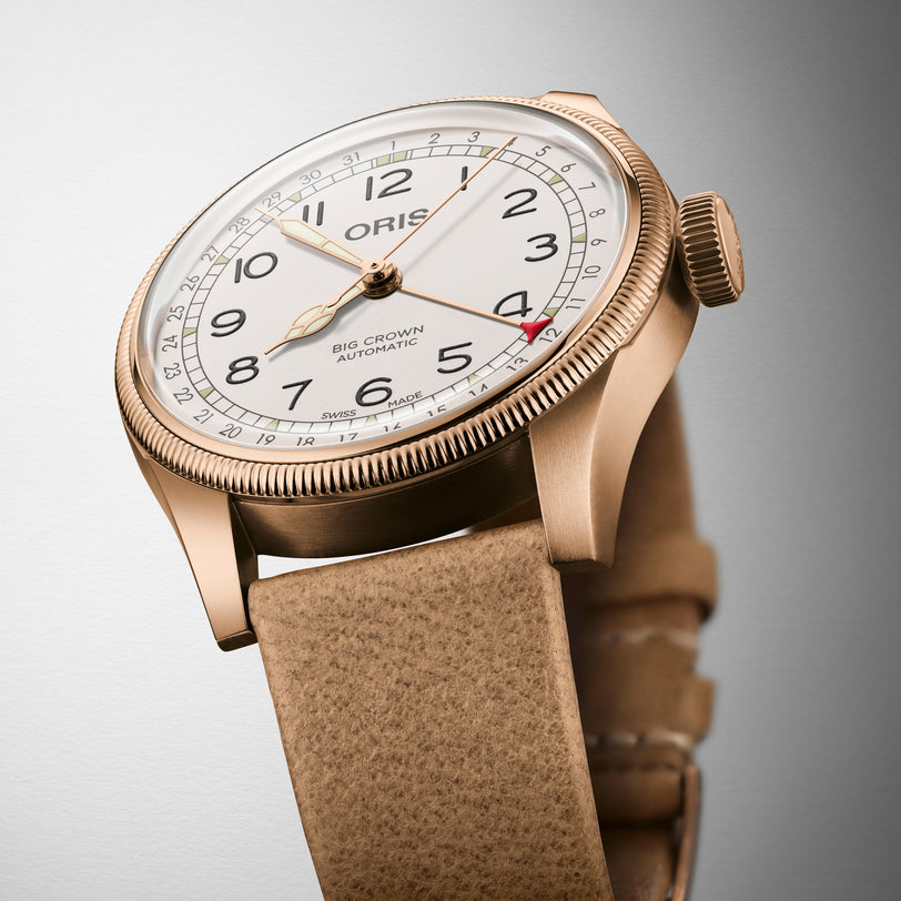 The Oris Big Crown Father Time Limited Edition features a beige leather strap, bronze case, white dial with black numerals, and the Oris logo. Inspired by ProPilot watches, its hands and markers are clearly visible for easy reading.