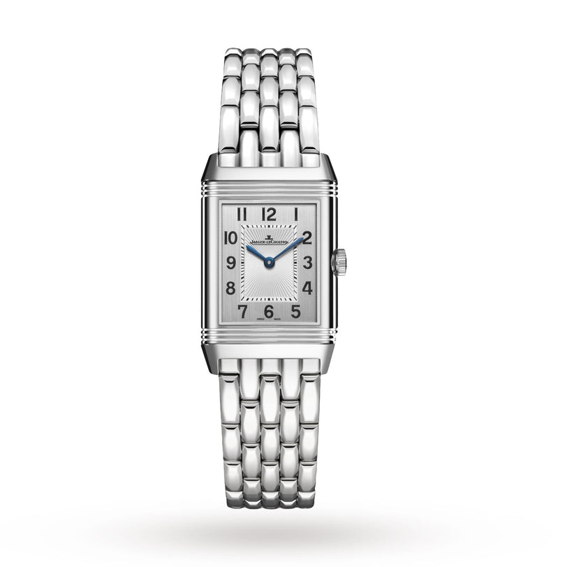 The Jaeger-LeCoultre Reverso Classic is a ladies’ watch with a rectangular silver case, metal bracelet, black Arabic numerals, blue hands on a white dial, and diamond bezel, shown against a plain white background.