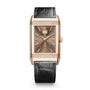 The Jaeger-LeCoultre Reverso Tribute Geographic is a rectangular pink gold watch with a brown dial, small seconds subdial, date window, and black leather strap, inspired by the iconic classic design.