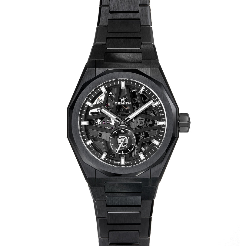 The black Zenith Defy Skyline Skeleton wristwatch, featuring a skeleton dial, silver hour markers, and a metal link bracelet, stands out with urban style and displays its high-frequency automatic movement against a white background.