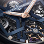 Close-up of the Ulysse Nardin Blast Tourbillon watch face, highlighting blue and rose gold hands, visible gears, and detailed mechanical components that exemplify haute horology.