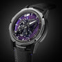 A close-up of the Ulysse Nardin Freak S WOS Centenary Exclusive, featuring its detailed exposed mechanical movement and black strap, set against a purple textured background signature to the brand.