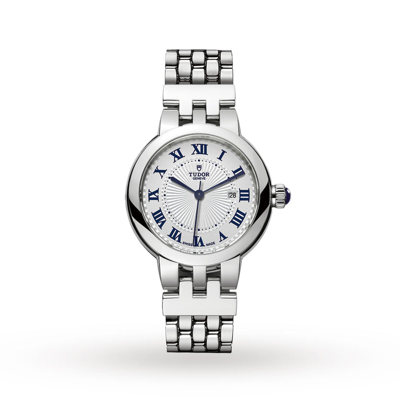The TUDOR Clair de Rose is a silver wristwatch featuring a white dial, blue Roman numerals, and a stainless steel link bracelet.