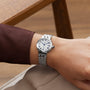 A TUDOR Clair de Rose silver wristwatch with a white face and Roman numerals worn on a persons wrist.