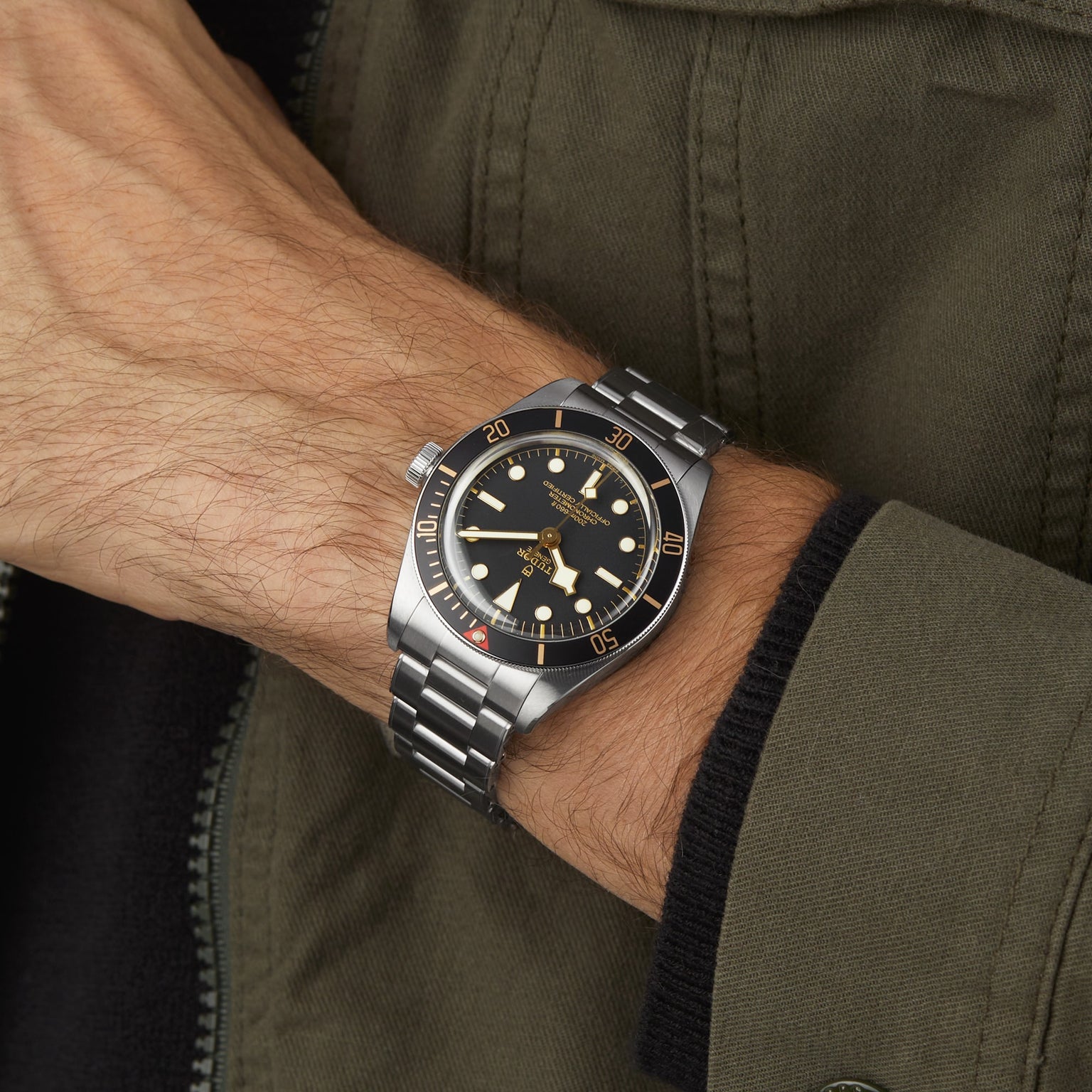 Wrist wearing the TUDOR Black Bay 58 with a green khaki jacket