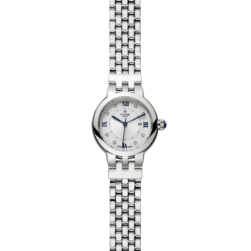 TUDOR Clair de Rose silver wristwatch with a round white face, Roman numerals, and metal link bracelet displayed on a white background.
