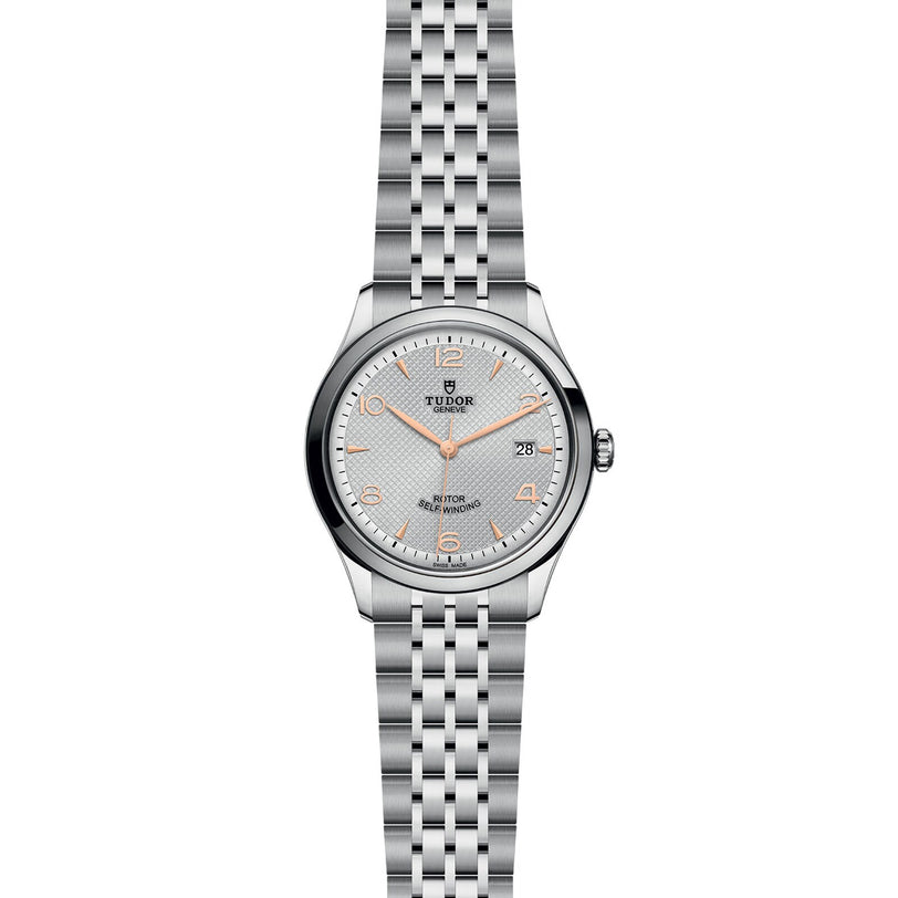 The TUDOR 1926 is a classic stainless steel wristwatch featuring a silver dial with orange hour markers, date display at 3 o’clock, and a five-link bracelet—ideal for fans of elegant mechanical timepieces.