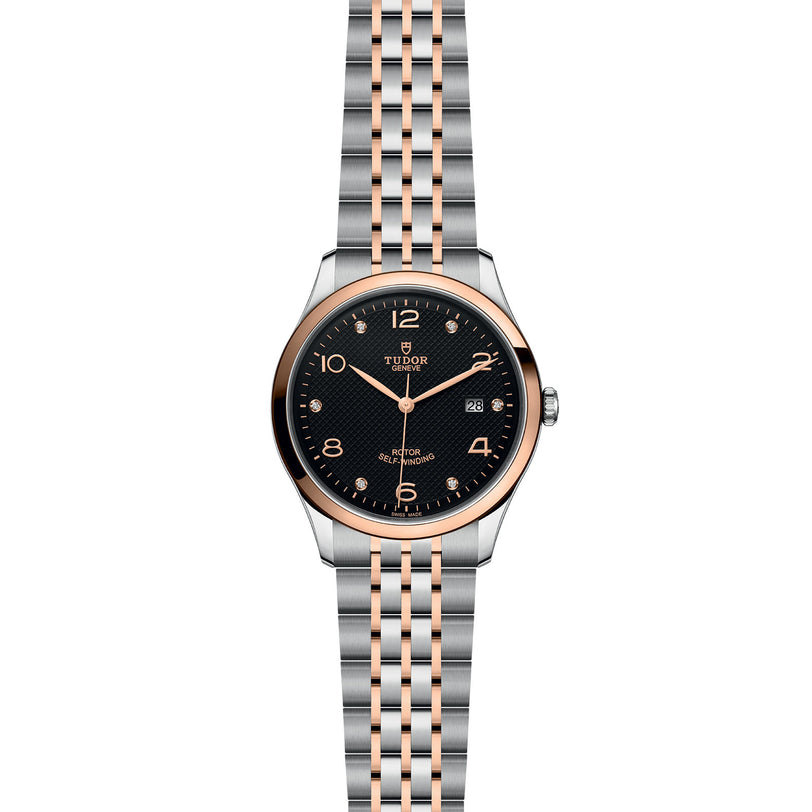 The TUDOR 1926 wristwatch features a black dial, gold-tone numerals, and a silver and rose gold bracelet, with date display at 3 o’clock.
