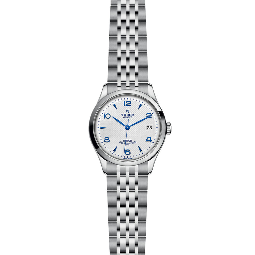 The TUDOR 1926 features a silver case, white dial with blue numerals and hands, a date window at 3 o’clock, and a stainless steel link bracelet—an excellent pick for fans of classic watch designs.