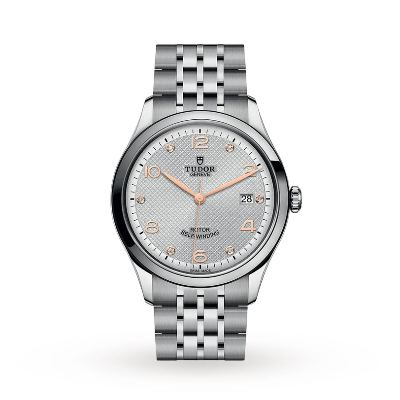 The TUDOR 1926 is a silver wristwatch with a textured light gray dial, rose gold markers and hands, a date display at 3 o’clock, and a metal bracelet—a refined mechanical timepiece from the TUDOR collection.