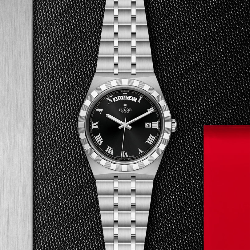 The TUDOR Royal, a stainless steel wristwatch with black dial, Roman numerals, and day-date display, exemplifies automatic sport-chic style against a textured black and red backdrop.