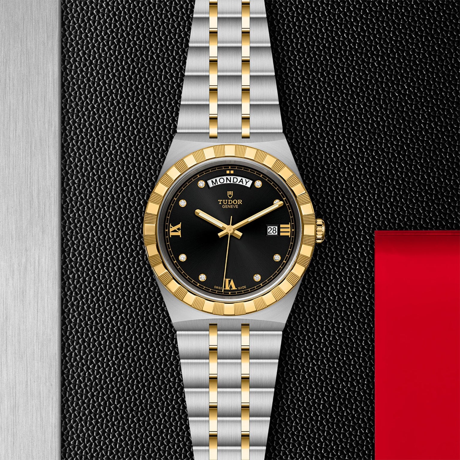 The TUDOR Royal watch features a black dial with gold accents and a two-tone silver and gold integrated bracelet, elegantly displayed on a textured black and silver background with red—highlighting its automatic sport-chic design.