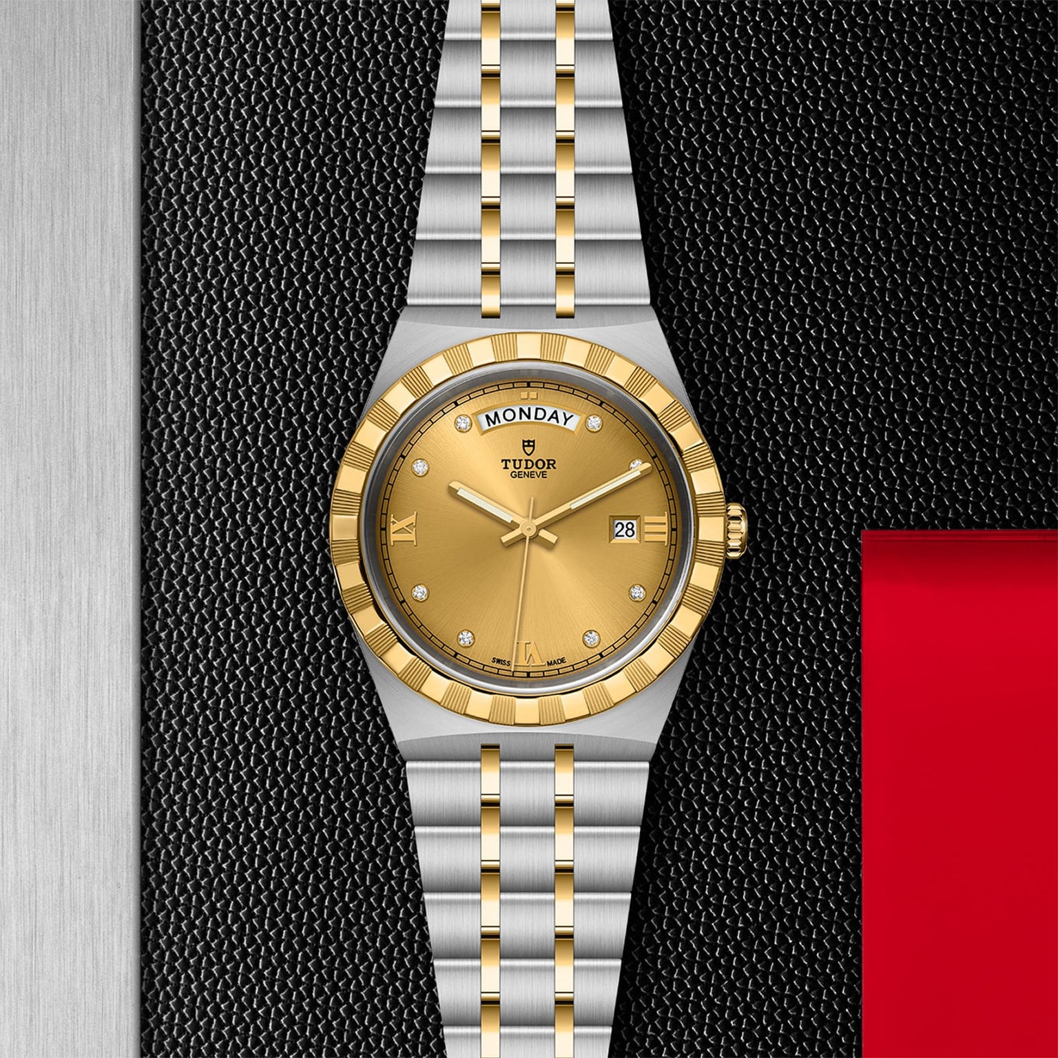 The TUDOR Royal wristwatch features a gold dial with day and date display, diamond hour markers, and a stainless steel and gold bracelet, showcased against a textured black background.