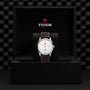 A classic and elegant TUDOR 1926 wristwatch with a white dial and brown leather strap is displayed in an open black TUDOR-branded box with a padded background.