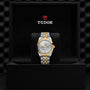 A TUDOR Black Bay One 36 S&G wristwatch with a two-tone metal band is displayed inside an open black presentation box featuring the TUDOR logo and emblem on the inner lid.