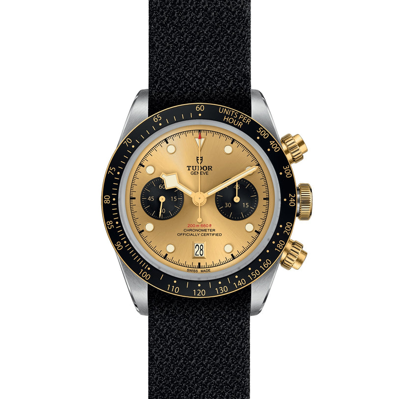 The TUDOR Black Bay Chrono S&G wristwatch features a gold and black dial, black bezel, gold subdials and pushers, and a black fabric strap—a bold addition to the TUDOR collection.